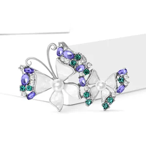 Elegante zilveren dubbele vlinderbroche met paarse stenen en parels op witte basis