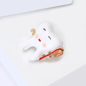 Macro shot of cartoon tooth brooch with enamel red toothbrush and golden metallic finish