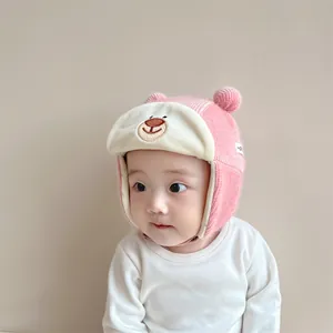 Detail of pink knitted winter baby hat with bear embroidery and soft ear flaps