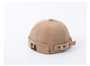Dettaglio del berretto in velluto a coste beige per bambini con ricamo CA e fibbia