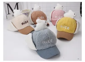 Detalle de gorros de aviador de lana de cordero para niños con conejo de peluche