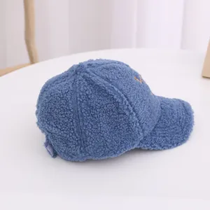 Close-up of blue fleece baseball cap with orange embroidery on a white pedestal