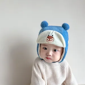 Close-up of blue knit baby bear hat with dual pom-poms and warm ear flaps for winter