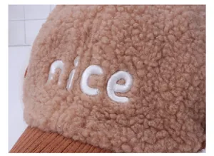 Detalle de textura de forro polar sherpa marrón y bordado blanco en gorro infantil