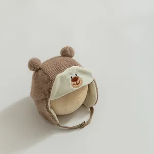 Close-up of winter baby hat with bear embroidery and soft white fleece lining detail