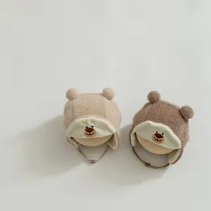 Close-up of knit baby bear hats with ear flaps and embroidery on wooden display stands