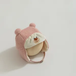 Detail of pink knitted baby trapper hat with bear embroidery and soft ear flaps