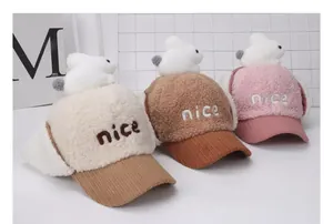 Detalle de gorros de invierno para niños con conejitos en vellón crema, marrón y rosa