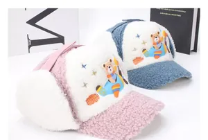 Close-up of children winter earflap hats featuring cartoon bear aircraft embroidery
