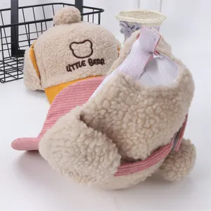 Detalle de gorros con orejeras de lana de cordero en amarillo y rosa con bordado Little Bear