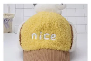 Detalle de gorro de invierno de felpa amarilla con bordado y decoración de panda blanco