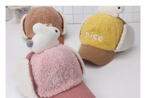 Detalle de orejas de conejo de peluche y bordado 'nice' en gorros de invierno para niños