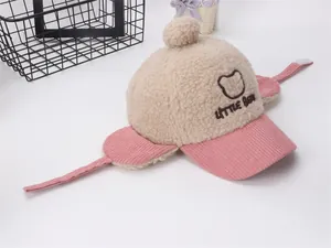 Detalle del gorro de pana rosa con orejeras, bordado de Little Bear y pompón de felpa