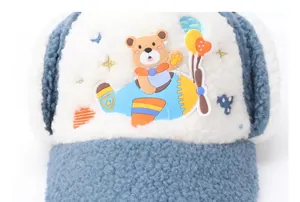Detail of winter trapper hat showing soft white fleece and bear pilot embroidery