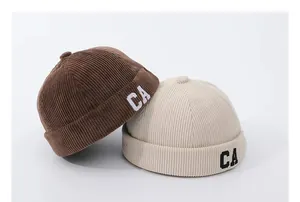 Dettaglio del velluto a coste e ricamo CA su cappelli docker per bambini marrone e beige