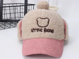 Detalle del gorro de invierno infantil con orejeras de felpa y bordado de oso