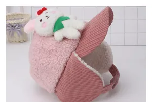 Detalle del gorro de invierno rosa con muñeco de conejo y orejeras de pana para niños