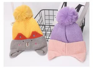 Detalle de gorros de punto para bebé con bordado de gato y pompones grandes de piel sintética