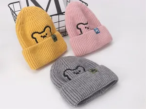 Dettaglio dei berretti invernali in maglia a coste con ricamo a forma di orso in tre colori