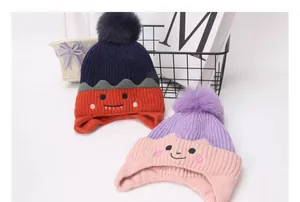 Detalle de gorro de punto con orejeras y pompón suave para niños pequeños