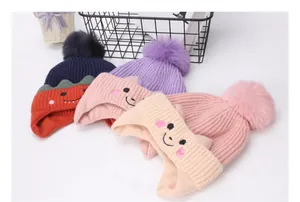 Detalle de gorros de punto para bebé con pompones y bordados en varios colores