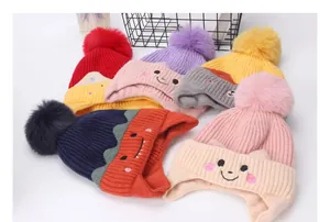 Detalle de gorros de punto para bebé con pompones suaves y bordados infantiles de colores