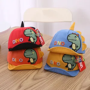 Detail of four baby dinosaur baseball caps with DINO embroidery on a wood surface