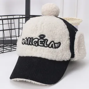 Detalle de gorra de invierno con pana negra, orejeras de forro polar blanco y pompón arriba