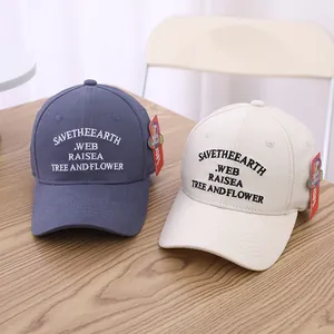 Detail der Save The Earth Stickerei auf marineblauen und beigen Baumwoll-Basecaps