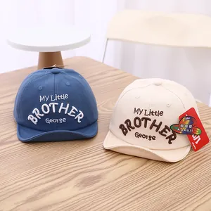 Detail of soft brim baby baseball caps in blue and beige with My Little Brother embroidery