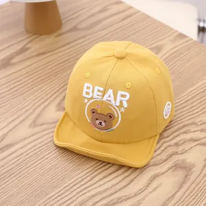 Gros plan d'une casquette de baseball jaune pour bébé avec broderie ours et texte BEAR