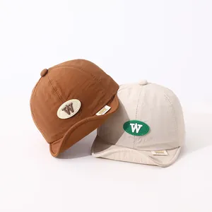 Detail of brown and cream soft-brim baby baseball caps with rubber W letter patches