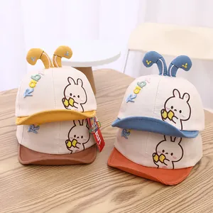 Détail de casquettes bébé bicolores avec oreilles de lapin et broderie mignonne