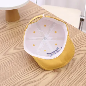 Detail view of the soft cotton inner lining and adjustable strap on this yellow baby cap