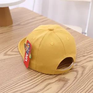 Detail of yellow cotton baby baseball cap with adjustable velcro strap on wood table