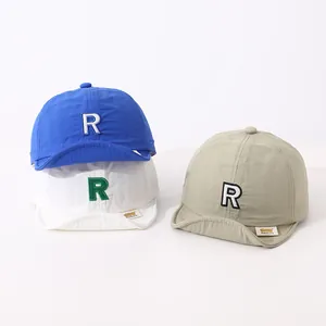 Detailed view of quick-dry baby baseball caps with R embroidery in blue, white, and khaki