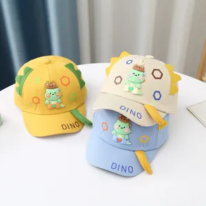 Close-up of cute cartoon dinosaur baseball caps in yellow, beige and light blue cotton