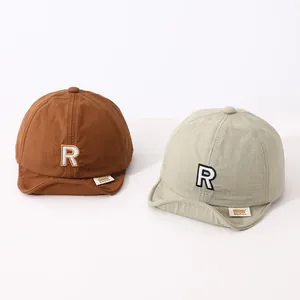 Detail of baby soft-brim baseball caps in brown and mint green with R embroidery