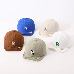 Detail of baby soft brim baseball caps with R embroidery in five different pastel colors