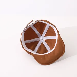 Internal view of brown baby baseball cap showing white reinforced stitching and metal rivets
