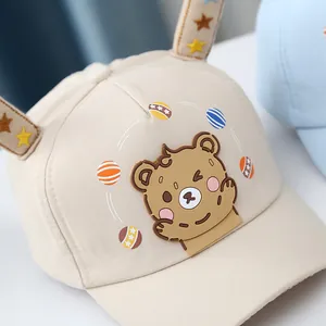 Close-up of beige baby baseball cap featuring cartoon bear patch and star printed ears