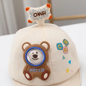 Dettaglio del berretto beige per neonati con toppa a orsetto di peluche e ricami colorati