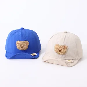Detail view of quick-dry baby baseball hats in blue and beige with cute 3D bear patches