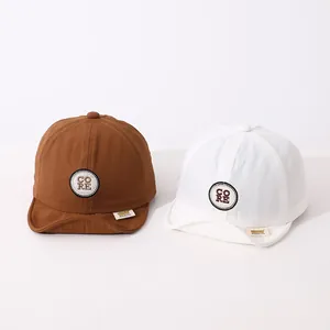 Detail of baby soft-brim baseball caps in brown and white with CORE embroidery