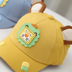 Dettaglio del cappellino giallo per neonati con toppa a leone e orecchie in 3D