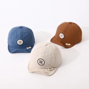 Detail of soft brim baby baseball caps in navy, beige, and brown with CORE embroidery