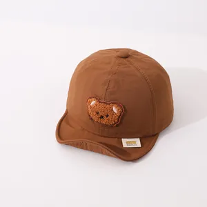 Detail of baby soft brim baseball cap featuring a cute brown plush teddy bear patch