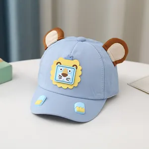 Dettaglio cappellino neonato con orecchie 3D e applicazione leone su tessuto blu chiaro