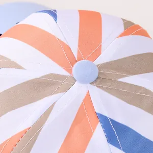 Top view of colorful striped baseball cap showing blue button and twill fabric texture