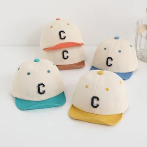 Dettaglio di cappellini per neonati con visiera morbida e ricamo C in vari colori